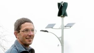 Chris Teo-Sherrell with the recently erected solar and wind powered street light