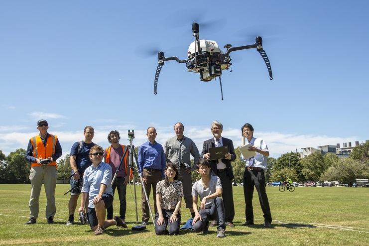 Yokohama National University and UC academics and students, including UC WRC Research Leader Dr Graeme Woodward (standing centre) and Professor Ryuji Kohno (standing second from right) watch while UC Senior Research Engineer Kelvin Barnsdale (far left) controls a UC drone